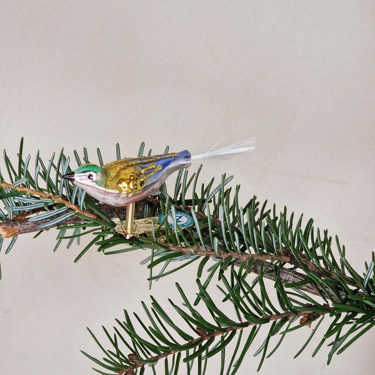 5cm sittande fågel i blått, guld och grönt - Julstämning.se