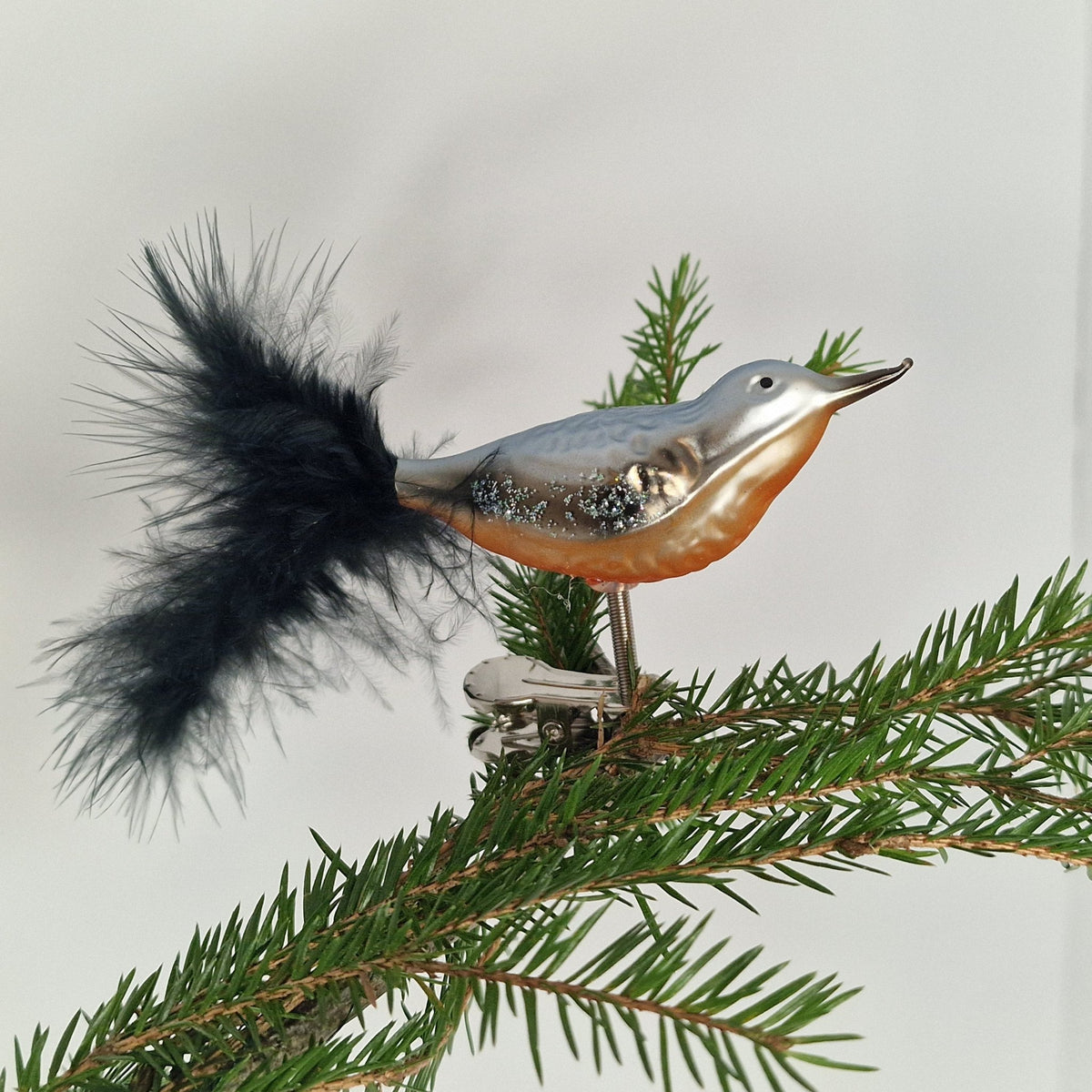 7cm sittande glansig fågel i blå grå och orange/rött - Julstämning.se